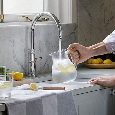 Man filling a jug with chilled filtered water from a kitchen tap.