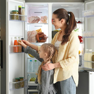 Mother and daughter choosing a drink from a fully stocked fridge filled with healthy food &ndash; Link to Refrigeration
